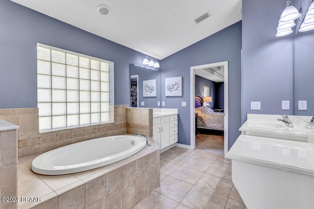 bathroom featuring tiled bath, vanity, lofted ceiling, and tile patterned flooring