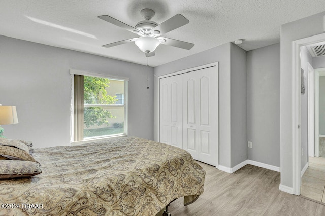 bedroom featuring ceiling fan, light hardwood / wood-style floors, a textured ceiling, and a closet