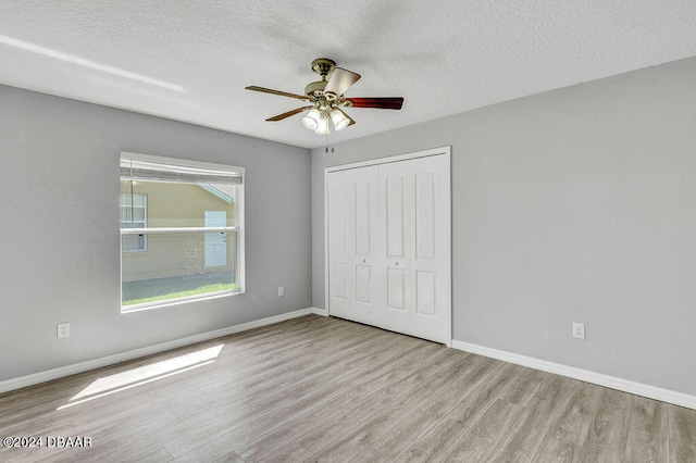 unfurnished bedroom with ceiling fan, a closet, a textured ceiling, and light hardwood / wood-style flooring