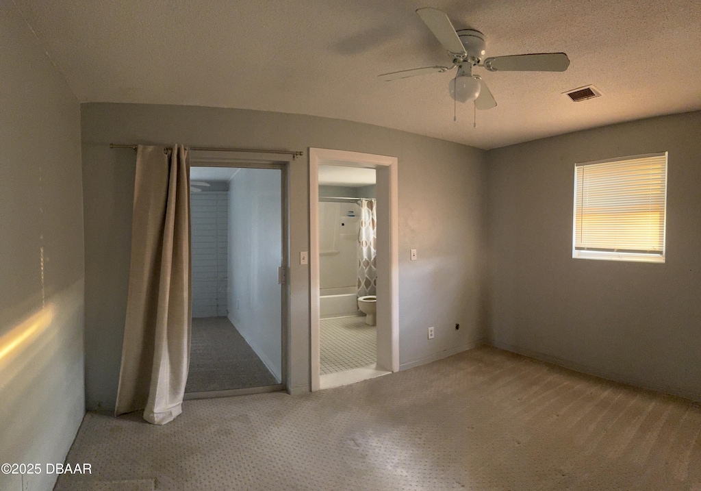 unfurnished bedroom featuring ceiling fan, ensuite bathroom, a textured ceiling, and carpet flooring