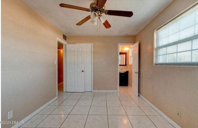 unfurnished bedroom with ceiling fan, light tile patterned floors, connected bathroom, and a closet