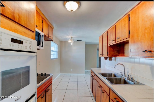 kitchen featuring backsplash, sink, light tile patterned floors, and white appliances