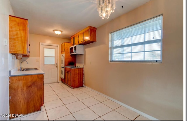 kitchen featuring sink, double oven, backsplash, a chandelier, and light tile patterned floors