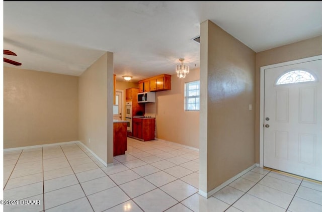 entryway featuring light tile patterned floors and ceiling fan with notable chandelier