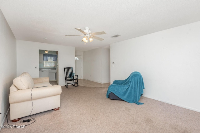 living area with a textured ceiling, ceiling fan, and light carpet