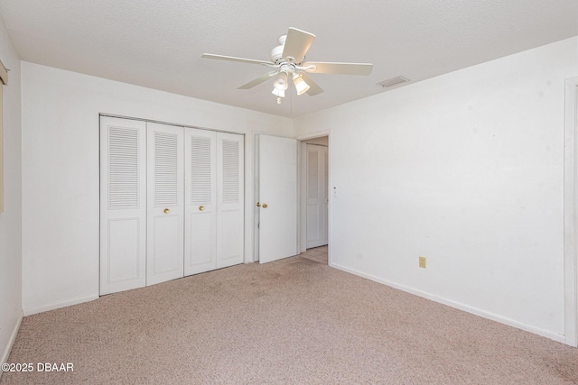 unfurnished bedroom with ceiling fan, light colored carpet, a textured ceiling, and a closet