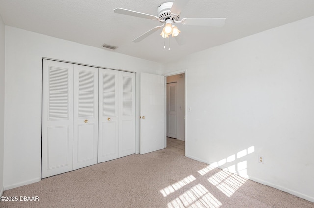 unfurnished bedroom with ceiling fan, a closet, and light colored carpet