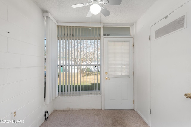 doorway to outside with ceiling fan, a textured ceiling, and light carpet