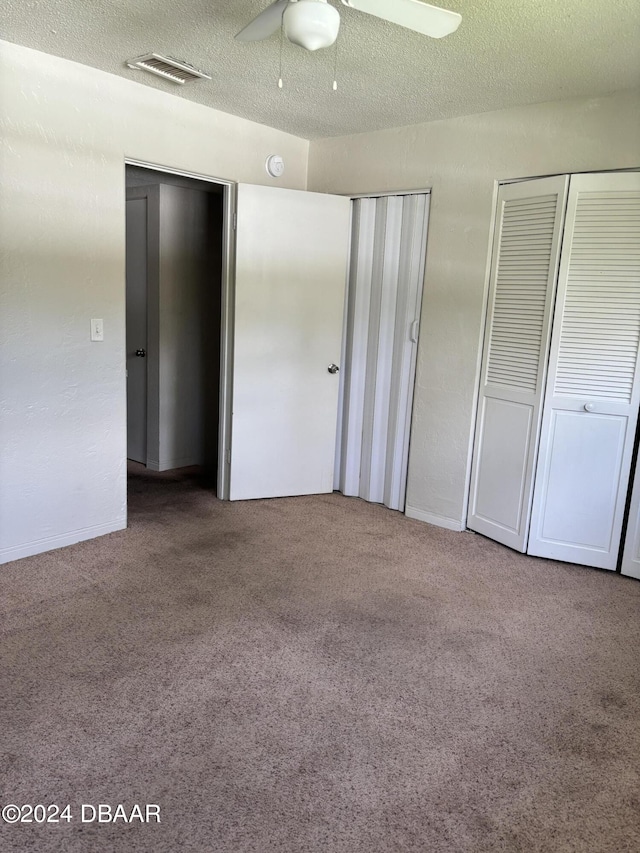 unfurnished bedroom with carpet flooring, ceiling fan, and two closets