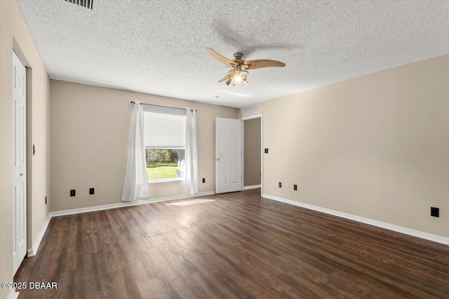 spare room featuring visible vents, baseboards, ceiling fan, dark wood-type flooring, and a textured ceiling