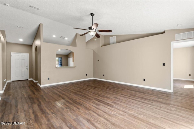 unfurnished living room featuring visible vents, a ceiling fan, wood finished floors, baseboards, and vaulted ceiling