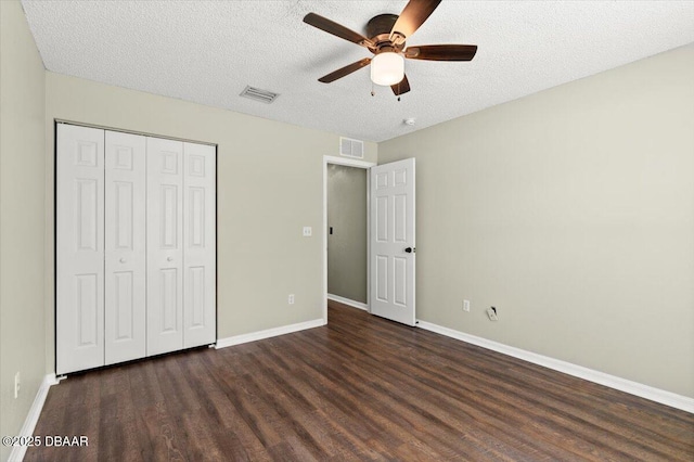 unfurnished bedroom featuring visible vents, a textured ceiling, a closet, and wood finished floors