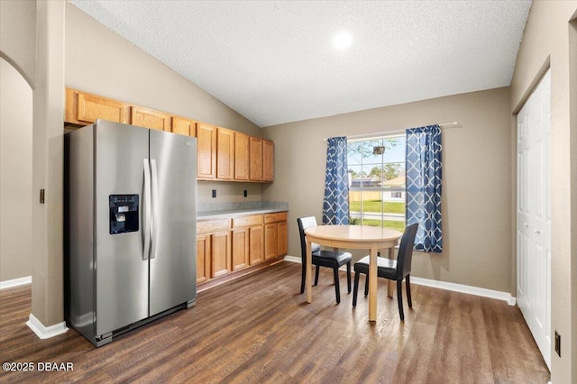 kitchen featuring stainless steel refrigerator with ice dispenser, a textured ceiling, baseboards, dark wood-style flooring, and vaulted ceiling