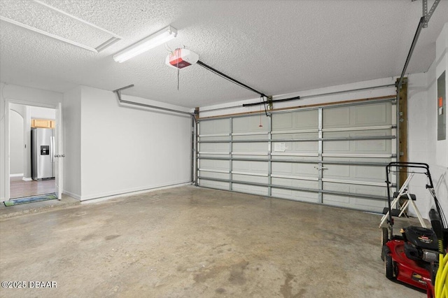 garage featuring stainless steel fridge, a garage door opener, and baseboards