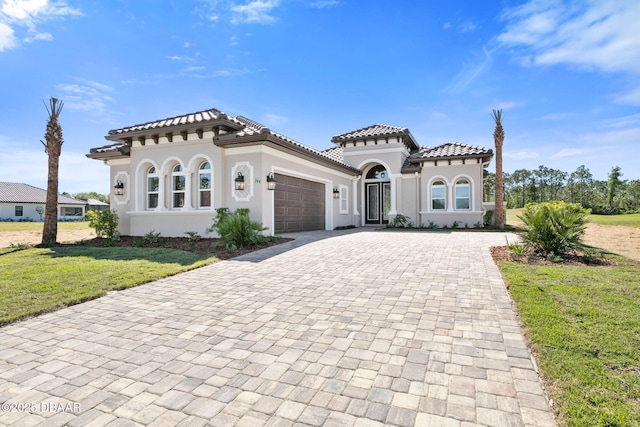 mediterranean / spanish-style home with a garage and a front lawn