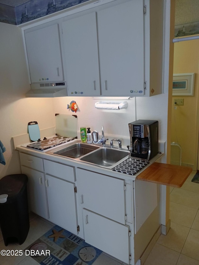 2043 S Atlantic Ave Unit 311, Daytona Beach, FL 32118 - kitchen featuring under cabinet range hood, a sink, white cabinets, light countertops, and light tile patterned flooring