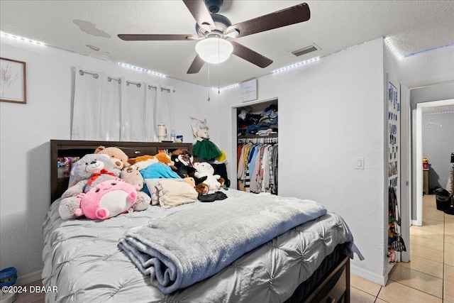 bedroom with a closet, a textured ceiling, light tile patterned floors, and ceiling fan