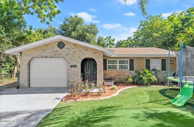 ranch-style house with a front lawn, a garage, and a trampoline