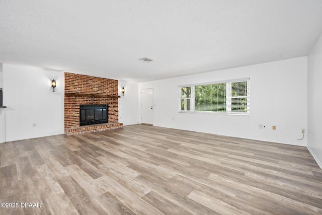 unfurnished living room with a fireplace, wood finished floors, and visible vents