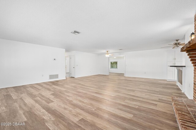unfurnished living room with a ceiling fan, visible vents, and light wood-style floors