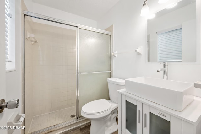 bathroom featuring vanity, a stall shower, toilet, and wood finished floors