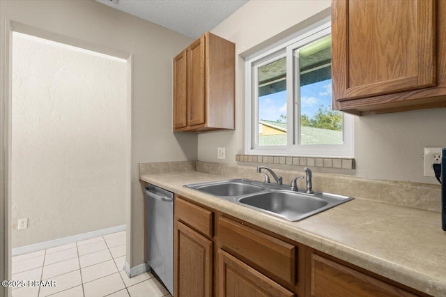 kitchen featuring light tile patterned flooring, sink, stainless steel dishwasher, and a textured ceiling