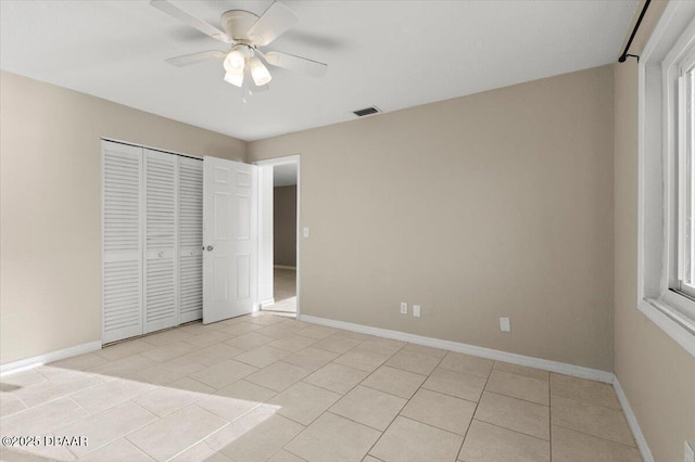 unfurnished bedroom featuring multiple windows, a closet, ceiling fan, and light tile patterned flooring