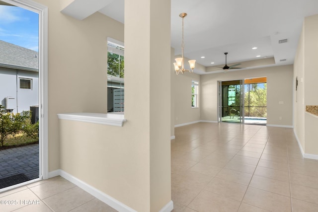 interior space with a raised ceiling and ceiling fan with notable chandelier