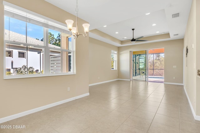 unfurnished room with a tray ceiling, ceiling fan with notable chandelier, and light tile patterned floors