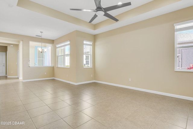 spare room featuring a raised ceiling, light tile patterned flooring, and ceiling fan with notable chandelier