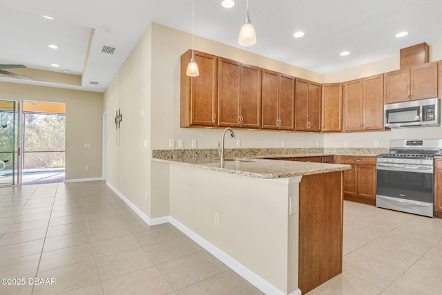 kitchen with sink, decorative light fixtures, appliances with stainless steel finishes, kitchen peninsula, and light stone countertops