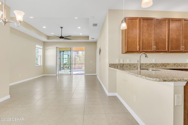 kitchen featuring sink, light stone counters, light tile patterned floors, kitchen peninsula, and pendant lighting