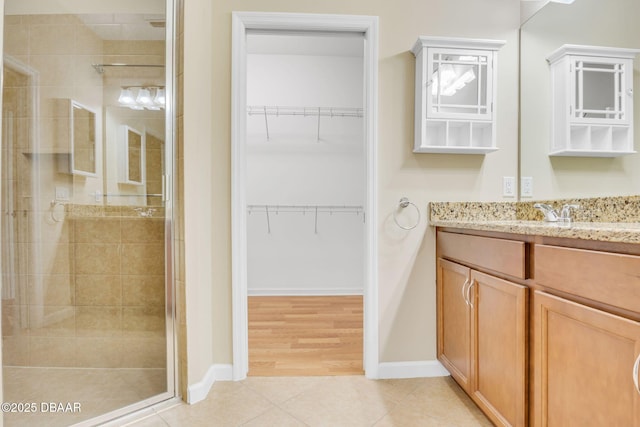 bathroom with tile patterned flooring, vanity, and walk in shower