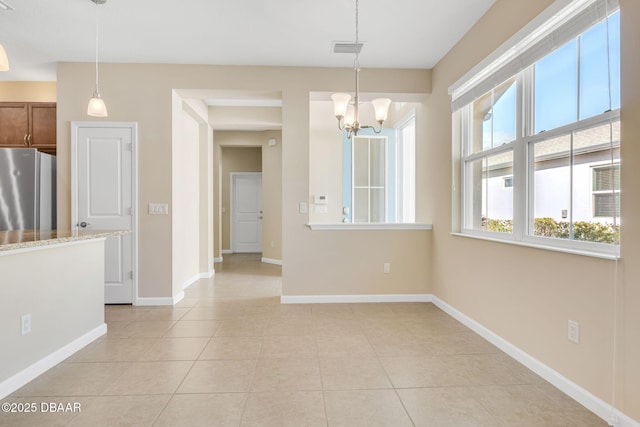 unfurnished dining area featuring light tile patterned floors and a notable chandelier