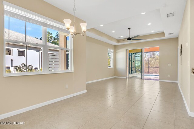 tiled spare room with a tray ceiling and ceiling fan with notable chandelier