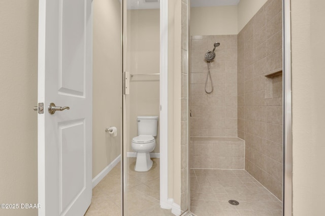 bathroom featuring a tile shower, tile patterned flooring, and toilet