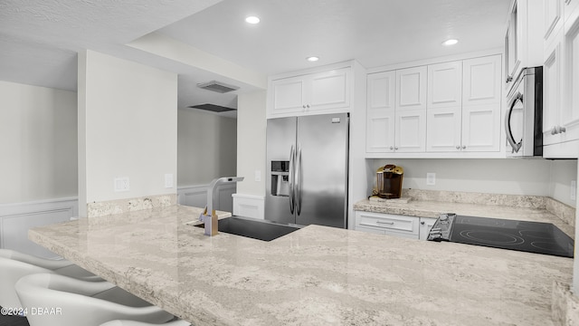 kitchen with light stone counters, white cabinetry, and stainless steel appliances