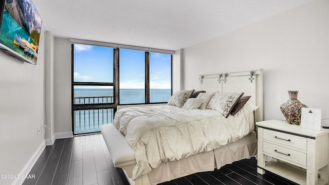 bedroom featuring a wall of windows, a water view, and dark hardwood / wood-style floors