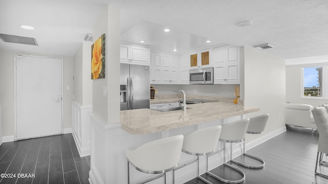 kitchen with white cabinets, a breakfast bar, kitchen peninsula, and appliances with stainless steel finishes