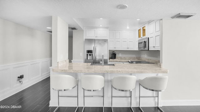 kitchen featuring kitchen peninsula, a kitchen breakfast bar, white cabinetry, and stainless steel appliances