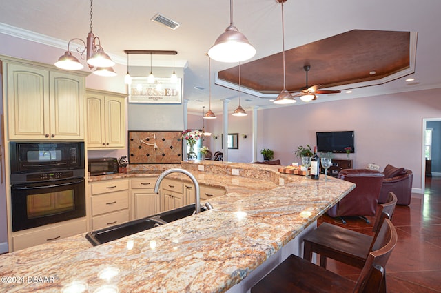 kitchen with light stone countertops, a raised ceiling, black appliances, and sink