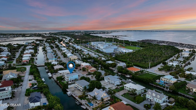 aerial view at dusk featuring a water view