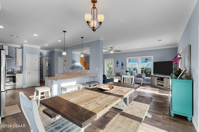 dining area featuring dark wood-type flooring, ornamental molding, and ceiling fan with notable chandelier