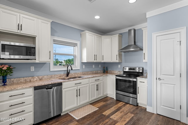 kitchen featuring dark hardwood / wood-style flooring, appliances with stainless steel finishes, wall chimney exhaust hood, and white cabinets