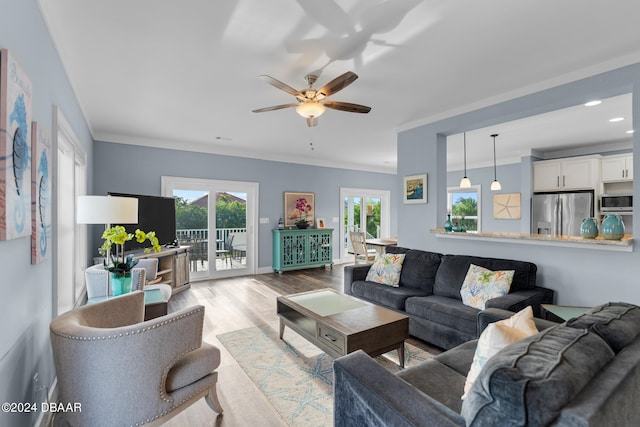 living room featuring light hardwood / wood-style floors, ceiling fan, and crown molding