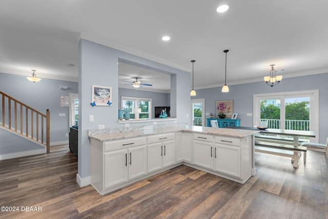 kitchen with white cabinetry, hanging light fixtures, light stone countertops, and dark hardwood / wood-style floors