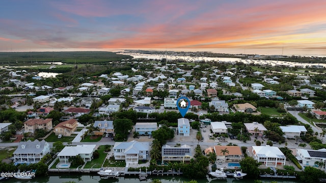 aerial view at dusk featuring a water view