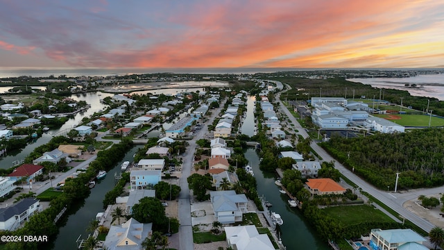 aerial view at dusk featuring a water view