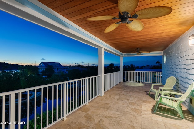 balcony at dusk featuring ceiling fan