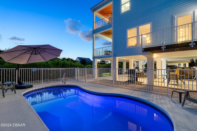 pool at dusk featuring a patio area